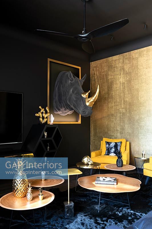 Eclectic living room with black painted walls and fabric Rhino trophy head on wall