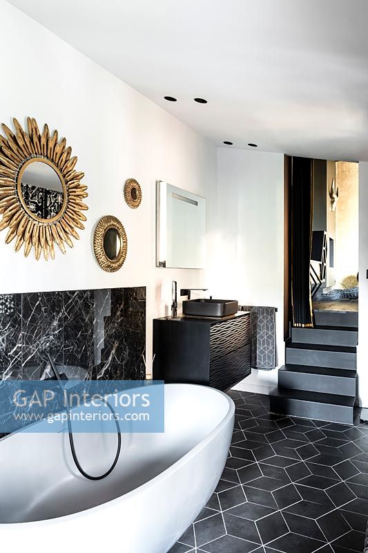 Freestanding bath in modern monochrome bathroom with steps up to bedroom 