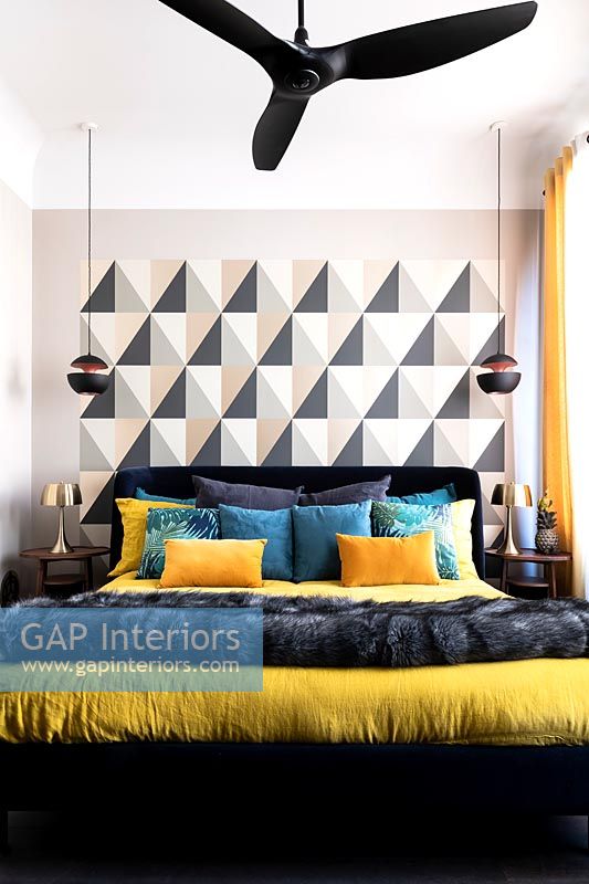 Black, white and yellow modern bedroom with patterned feature wall and ceiling fan