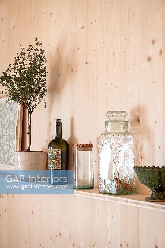 Glass jars and houseplant on kitchen shelf 