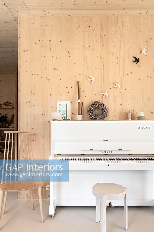 White upright piano in modern timber clad music room 