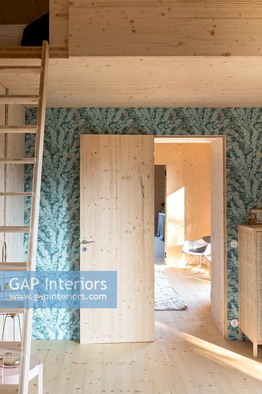 Open internal wooden door set in wallpapered feature wall