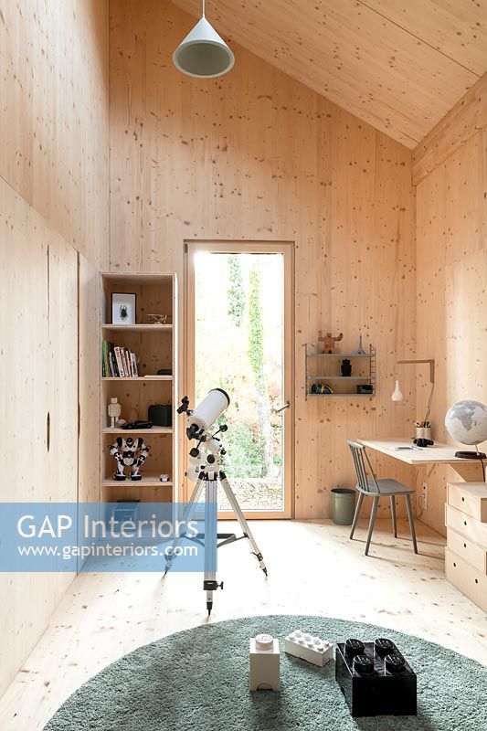 Timber clad modern children's room with telescope and desk