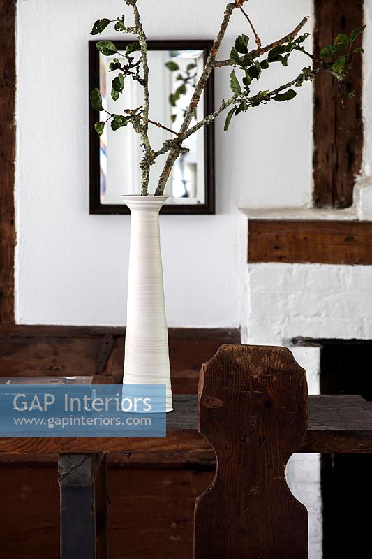 Long white vase with tree branches as arrangement in country dining room 