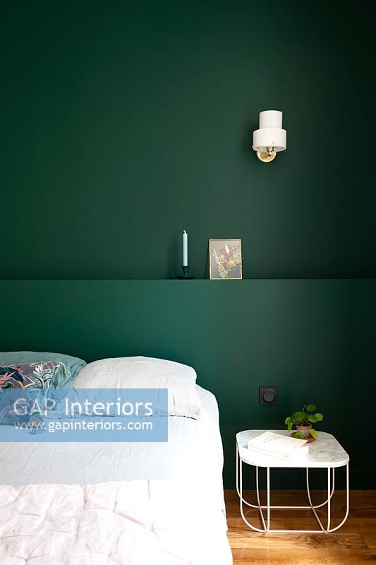 Dark green painted feature wall and headboard in modern bedroom 
