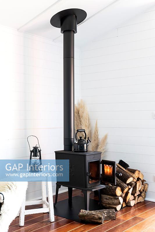 Black wood burning stove in white painted wooden cottage style living room 