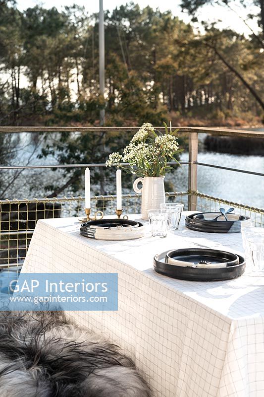 Outdoor dining table on balcony overlooking lake 