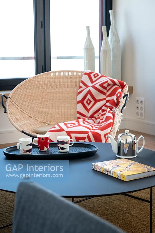 Colourful throw on round rattan chair in modern living room 