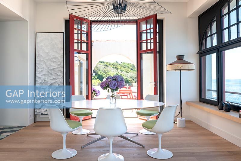 Modern dining room with view through open French doors to terrace with sea views 