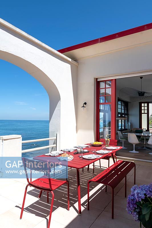 Red and white terrace with outdoor dining table and sea views 