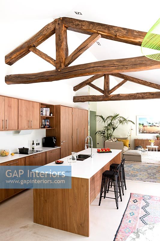 Exposed wooden beams over modern kitchen area in open plan living space 