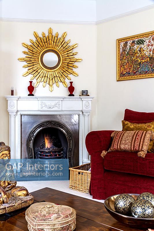 Large starburst mirror over mantelpiece in eclectic living room 