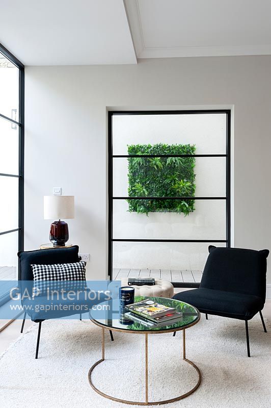 Small seating area with coffee table - living wall seen through window behind 