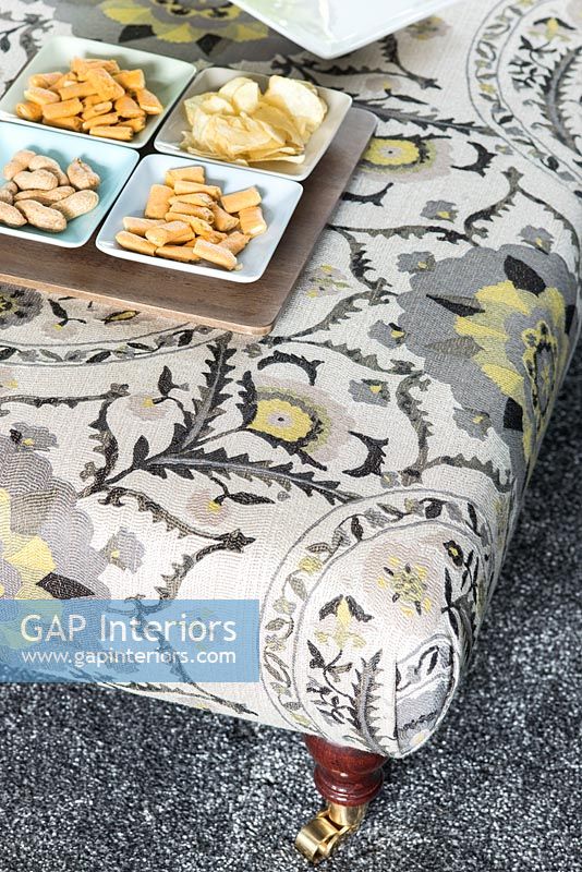 Patterned foot stool used as coffee table with tray of snacks