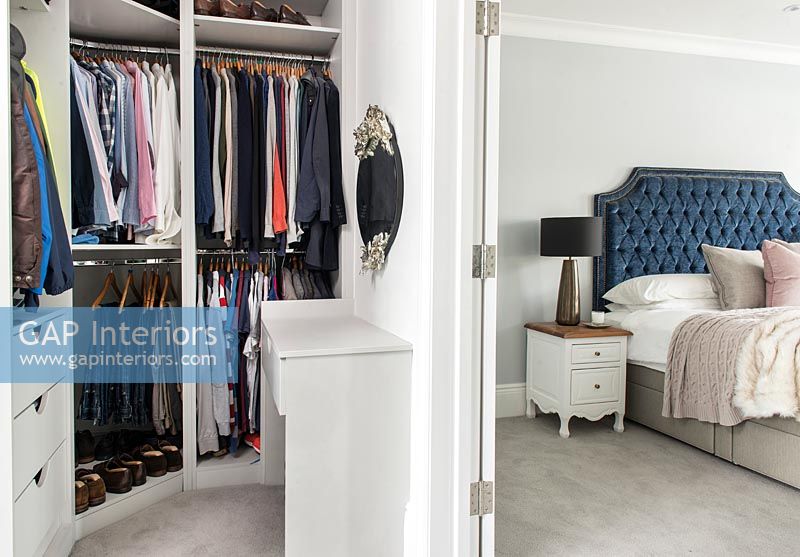 View of clothing hanging in large bedroom wardrobes 