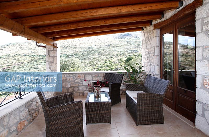 Covered terrace with seating area and view of hillside beyond 