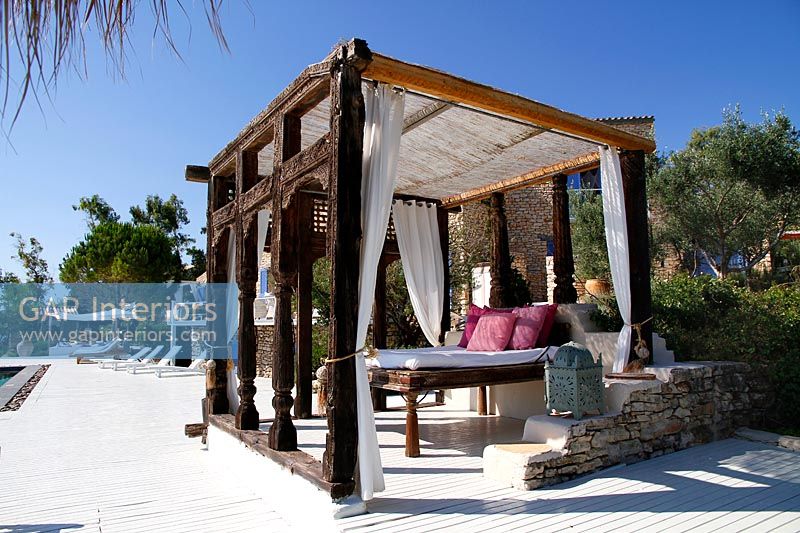 Decorative pergola with large bed on outdoor terrace 