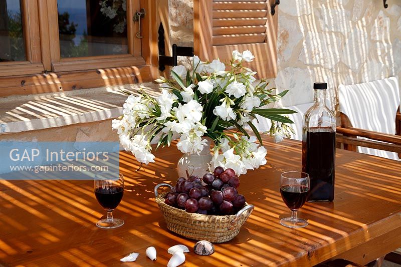 Flower arrangement, grapes and wine on outdoor dining table 