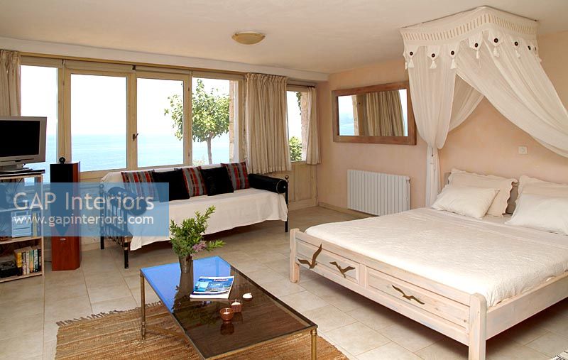 Modern country bedroom with canopy over bed and sea views 