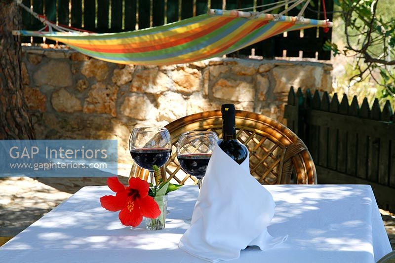 Wine on outdoor table with tablecloth and hammock in the background 