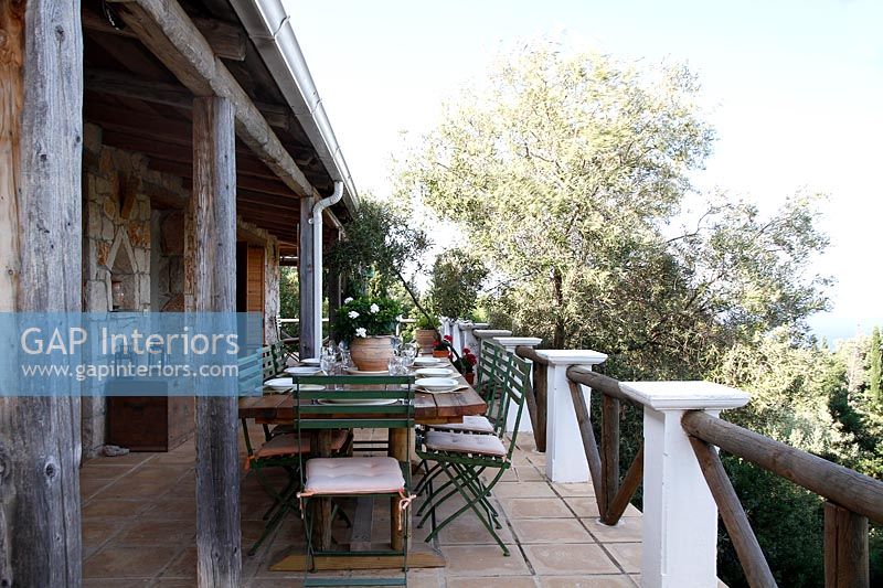 Rustic veranda with large dining table laid for lunch in summer 