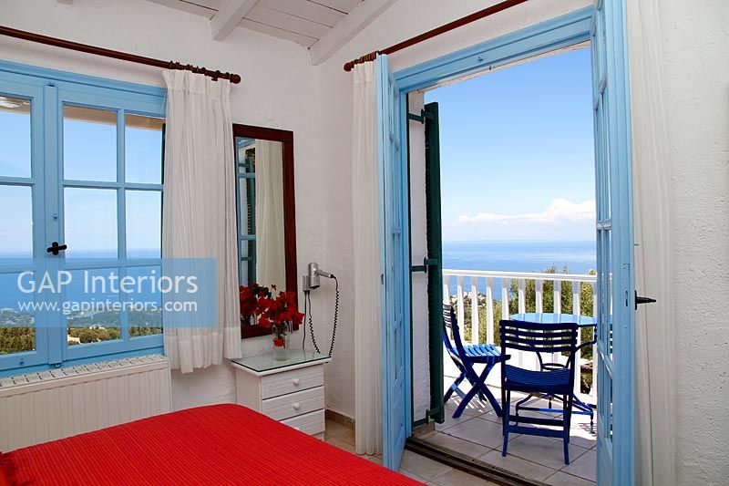 Mediterranean country bedroom with open French doors to balcony with sea views 