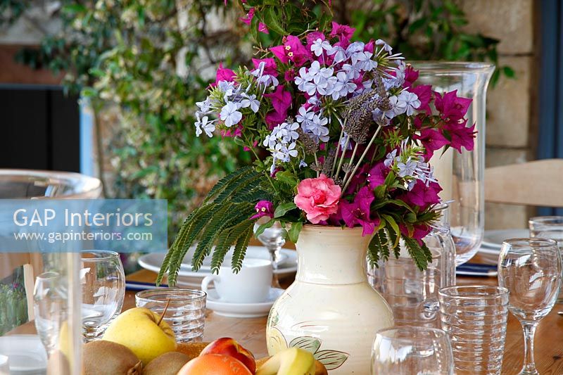 Detail of flower arrangement on outdoor dining table laid for lunch 