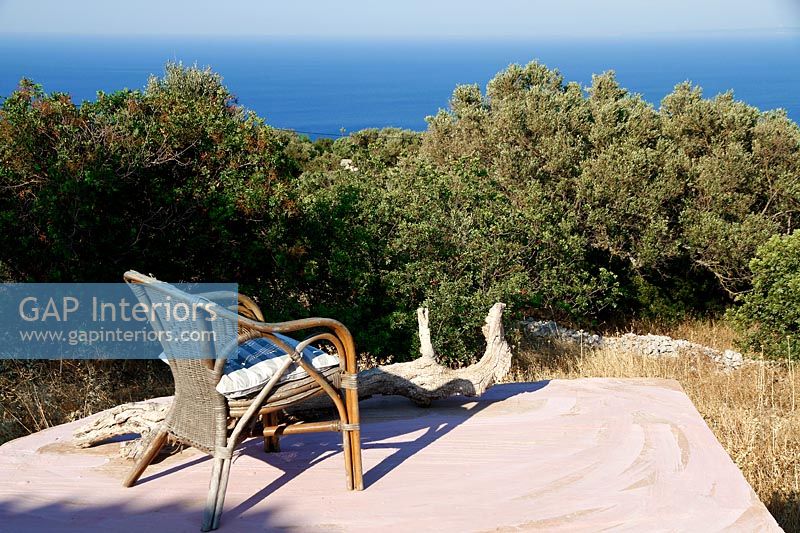Wicker armchair on stone platform with coastal views 