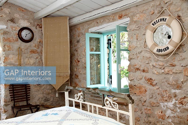 Country bedroom with exposed stone wall and maritime themed mirror 