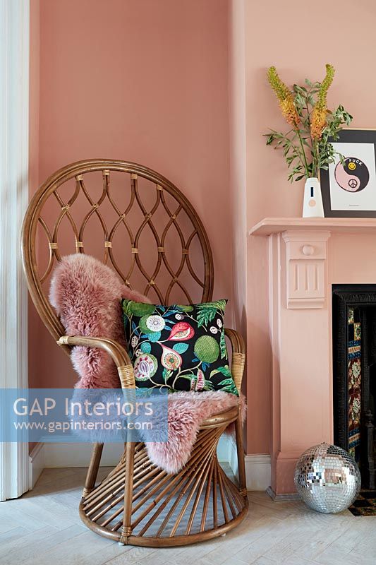 High backed wicker armchair in pink painted living room 