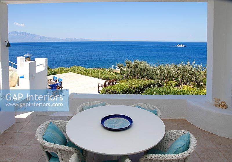 Table and chairs on shaded terrace with sea views 