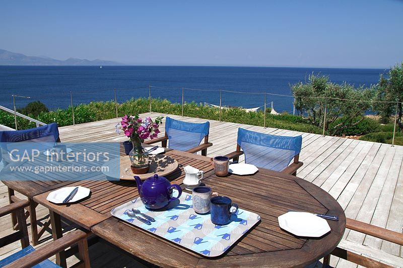 Wooden dining table on decking with sea views 
