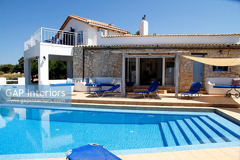 Swimming pool and outdoor seating area next to Mediterranean villa 