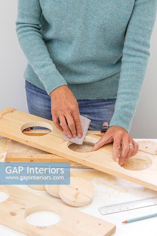 Woman using sandpaper to smooth the edges of the holes cut