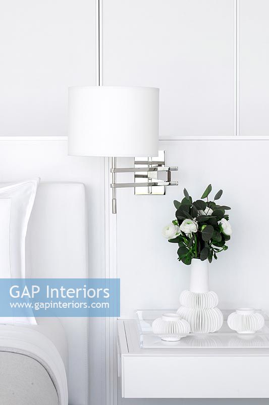 White bedroom furniture and wall mounted lamp detail 