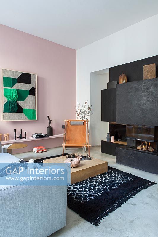 Black contemporary fireplace in modern living room with pink painted feature wall 