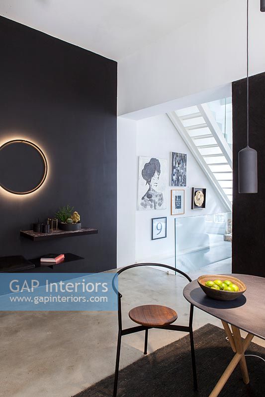 Contemporary dining room with illuminated circular light on black painted feature wall 