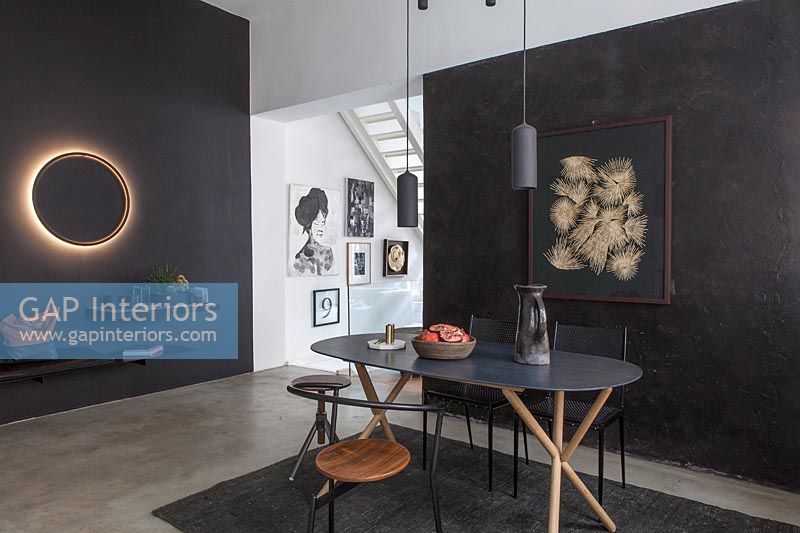 Contemporary dining room with illuminated circular light on black painted feature wall 