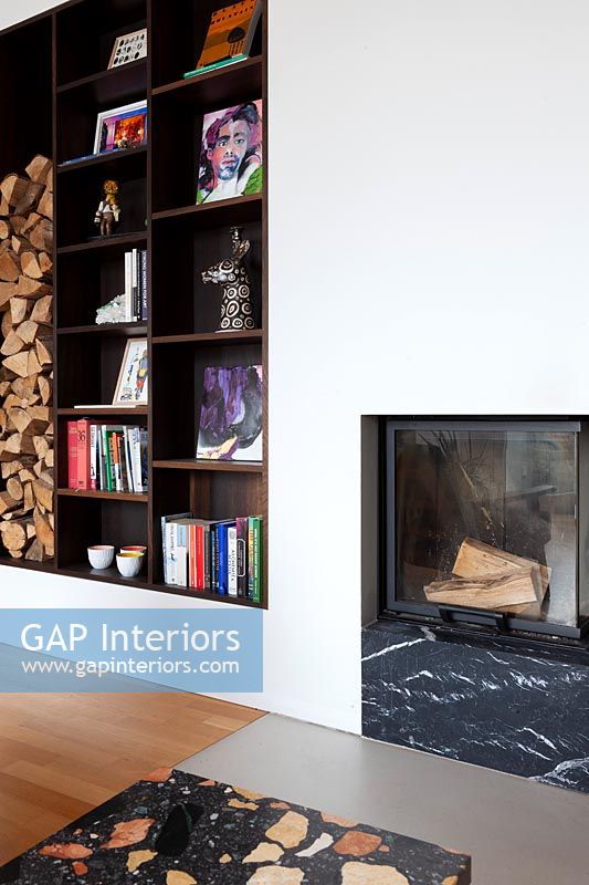 Built-in shelving with firewood storage and small fireplace in feature wall 