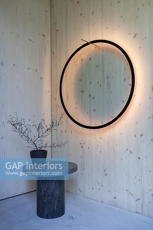 Black circular halo light on wooden wall with small marble table