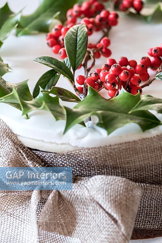Holly and berries decorating a hessian wrapped Christmas cake 