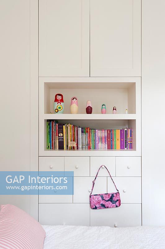 Display of toys and books on shelves in built-in wardrobes
