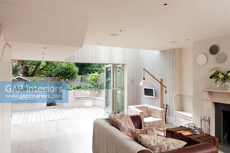 Modern living room with view of courtyard garden through open bifold doors 