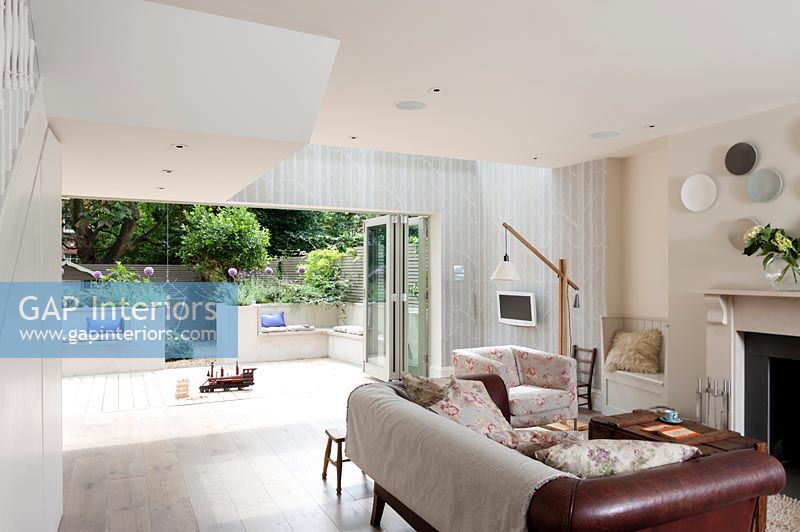 Modern living room with view to courtyard garden through open bifold doors 