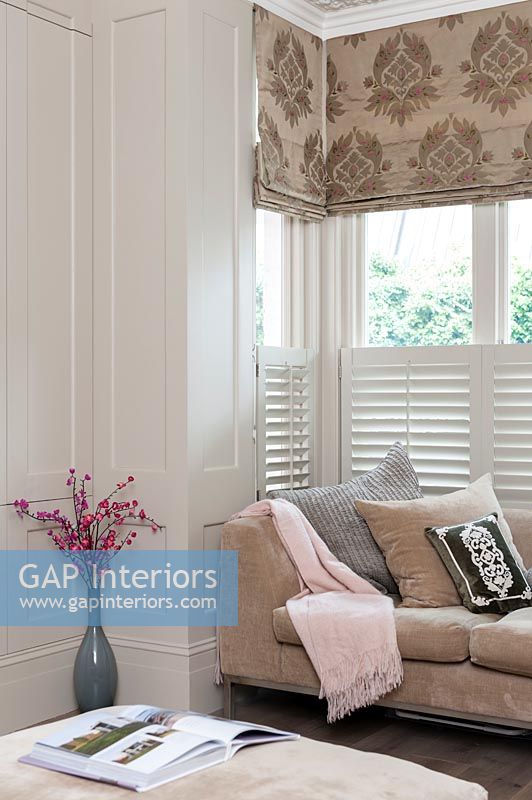 Modern living room with patterned roman blinds above slatted blinds 