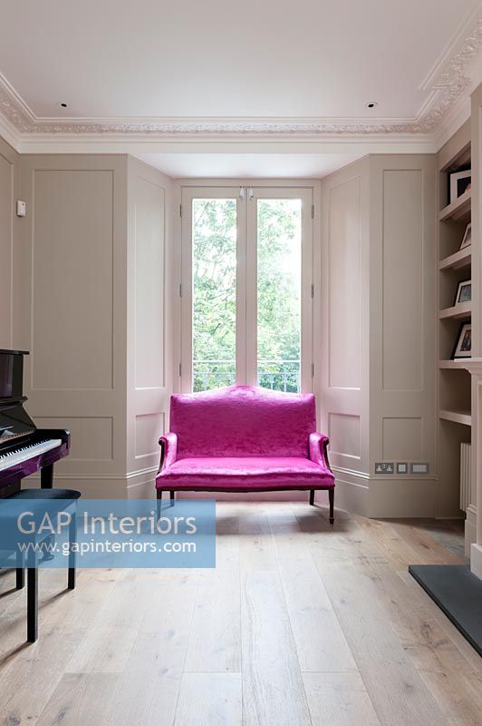 Bright pink two-seater sofa in classic living room 