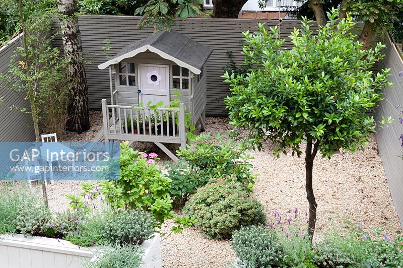 Overhead view of modern courtyard garden with decorative painted wooden playhouse 