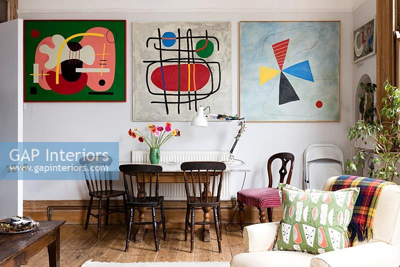 Dining area and wall of colourful modern artwork in open plan living space 