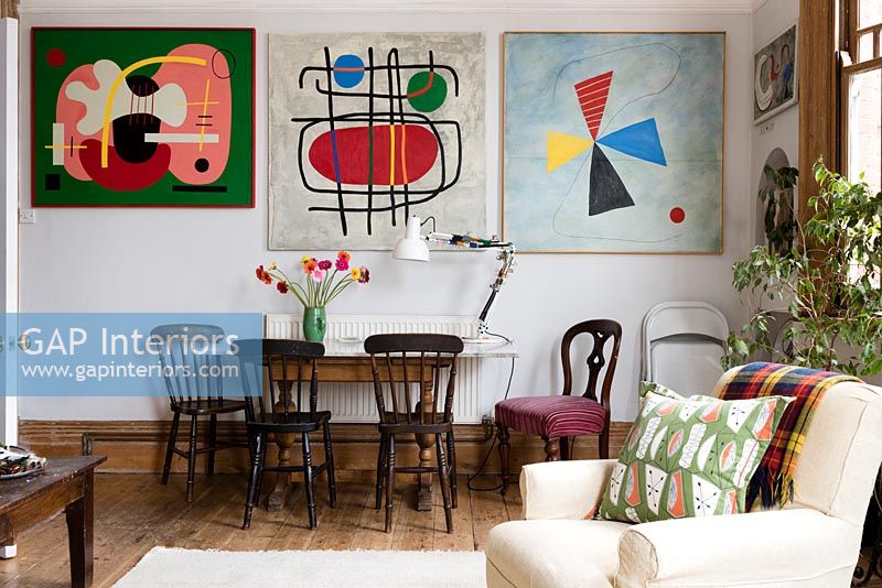 Dining area and wall of colourful modern artwork in open plan living space. 
Cushion by Nichollette Yardley-Moore www.vintagecushions.com