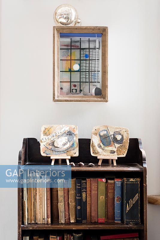 Vintage wooden bookcase with modern painted ceramics on shelf
